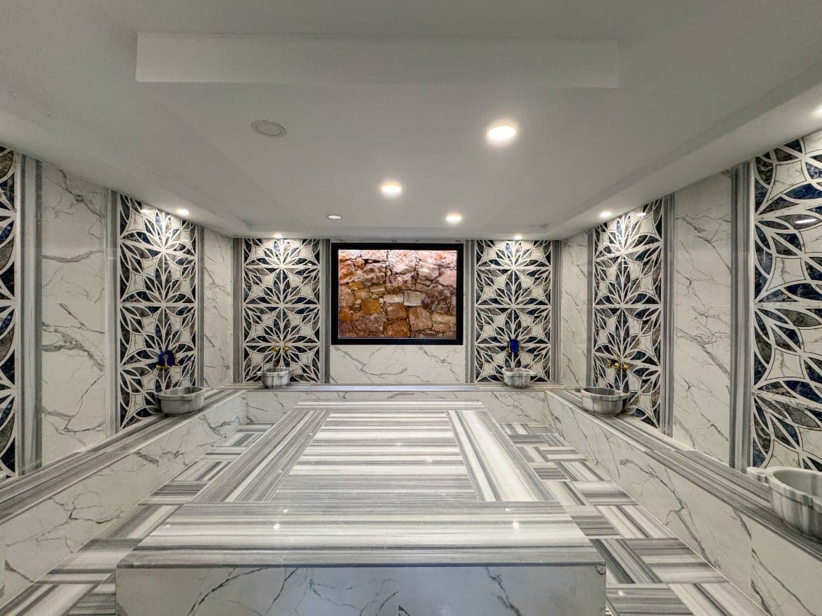 Aydınlatılmış hamam iç mekânında göbek taşı ve kurna sırası